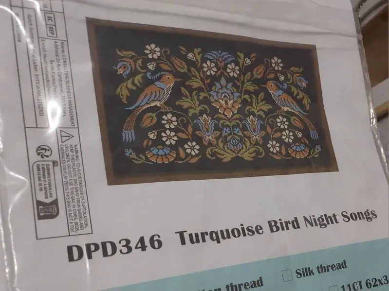 Buyer photo of the Turquoise Bird kit packet: the DPD346 folk bird design on black fabric shown on the pouch